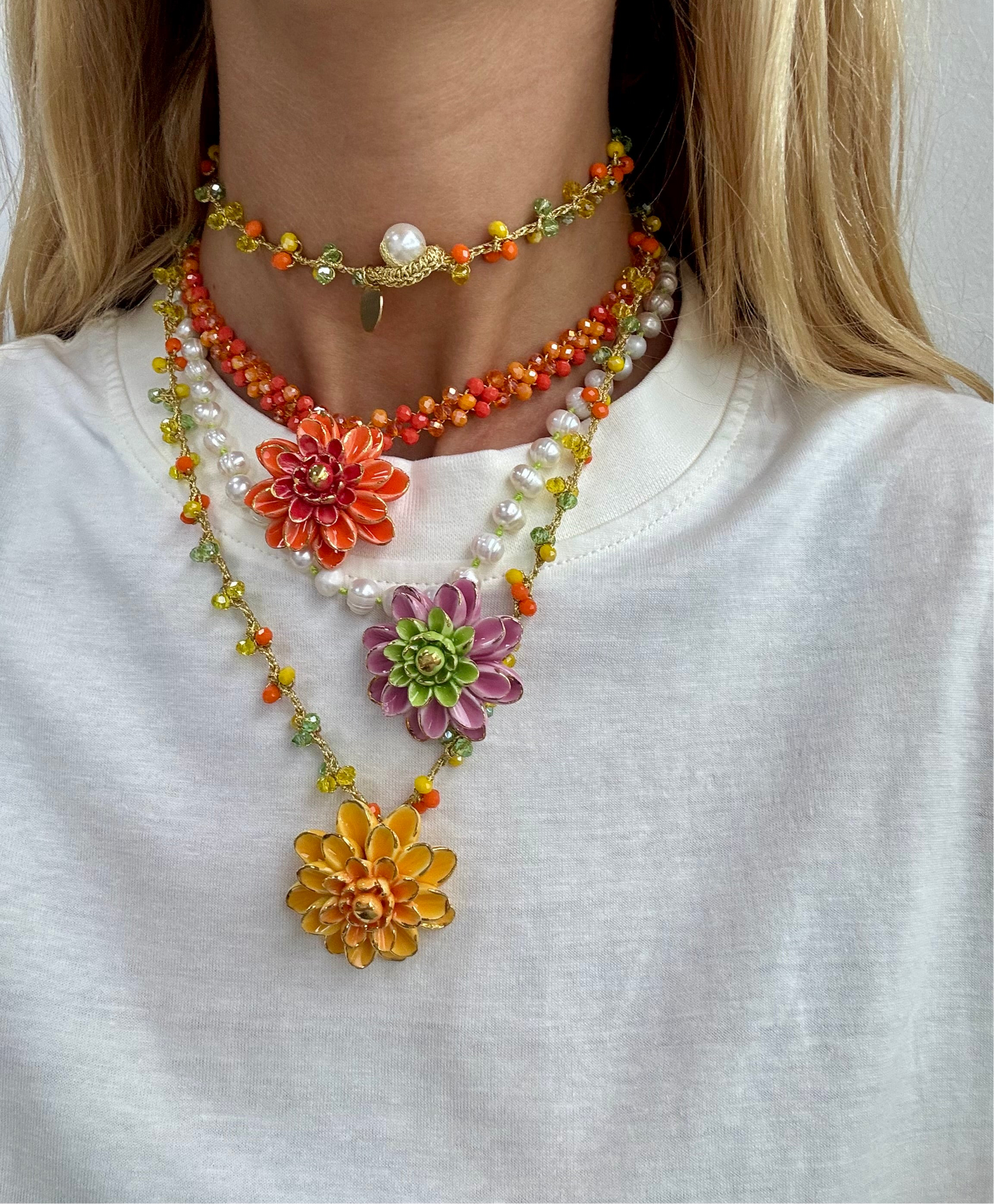 Collar Sofía con cuentas facetadas en naranja, amarillo y verde lima, con colgante de flor esmaltada en mostaza y detalles naranjas, sobre camiseta blanca con doble vuelta al cuello, combinado con el collar Alice y Fiorella. Cashfana.