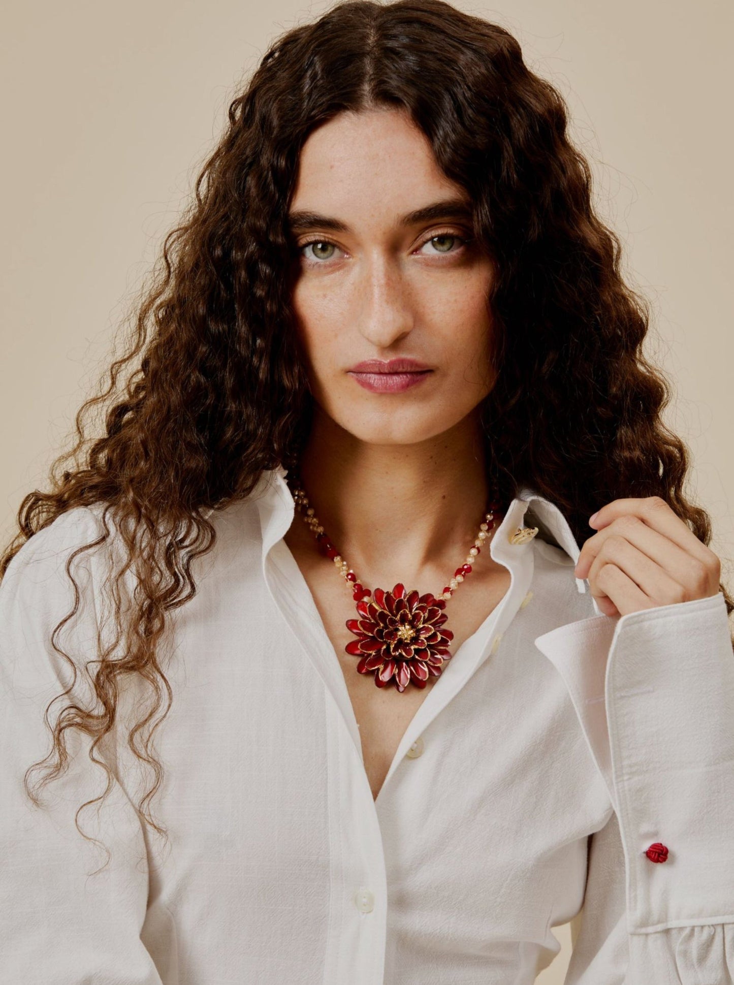 Collar Isabella con cuentas facetadas en rojo cereza y champán, con colgante de flor esmaltada en rojo intenso y detalles dorados, sobre modelo. Cashfana.