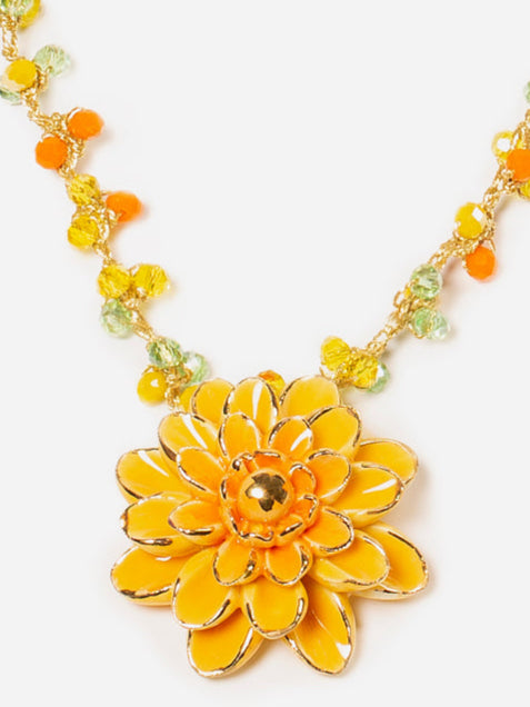 Collar Sofía con colgante de flor esmaltada en mostaza y detalles naranjas, sobre fondo blanco. Cashfana.