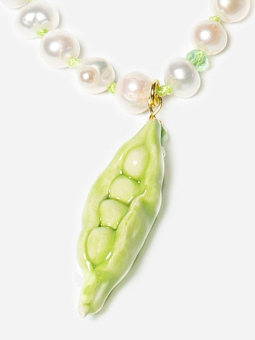 Collar largo de perlas naturales con cuentas verdes y nudos del mismo verde entre perla y perla, colgante de cerámica en forma de vaina de guisantes y cierre también decorado con perla, sobre fondo blanco. Cashfana.