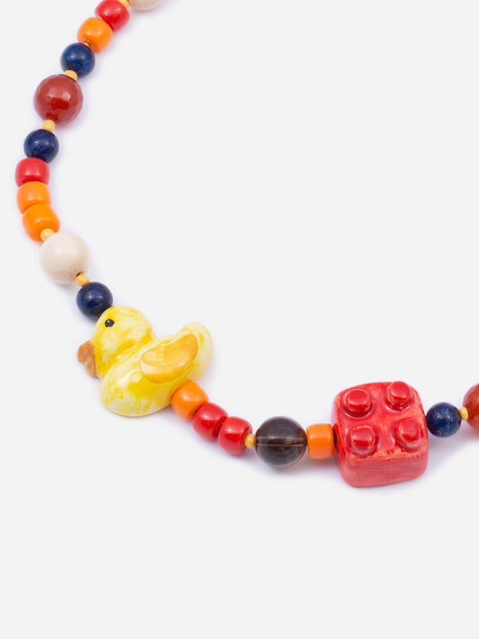 Collar con cuentas multicolor y charms de patito amarillo y bloque tipo LEGO rojo. Fondo blanco. Cashfana.