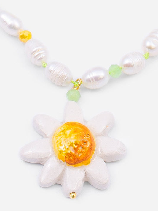 Colgante de flor esmaltada en blanco con centro dorado, sobre fondo blanco. Cashfana.