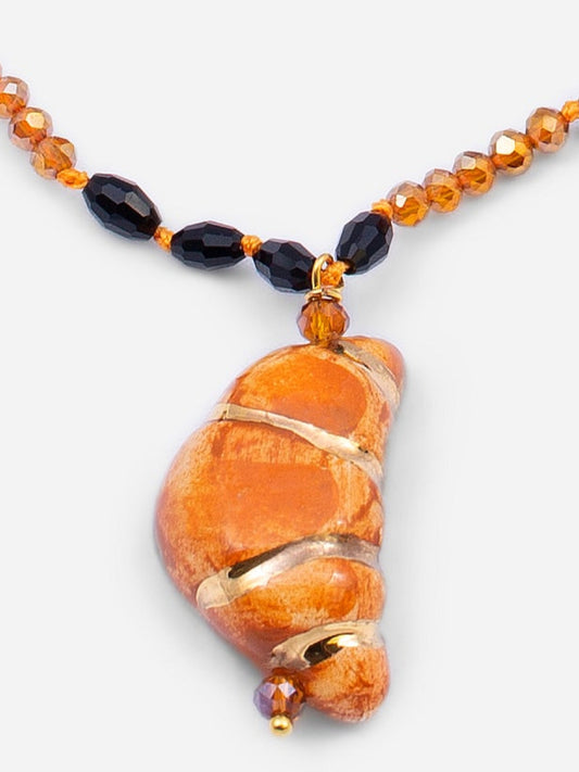 Detalle de collar croissant sobre fondo blanco