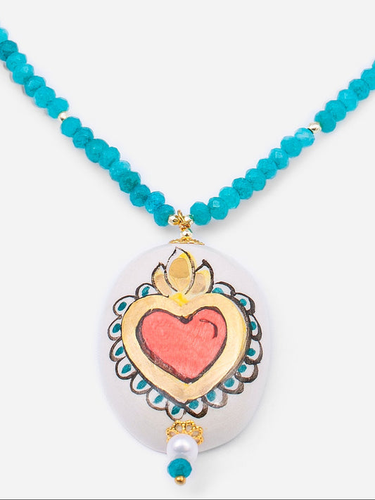 Colgante de cerámica en forma de corazón rojo con marco blanco decorado, sobre fondo blanco.