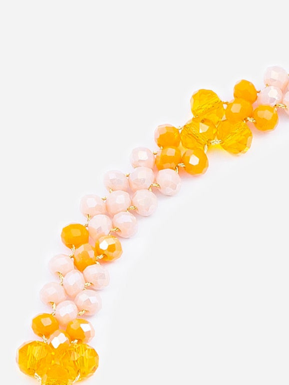 Collar corto con cuentas rosadas y amarillas cosidas con la técnica de crochet por un hilo dorado, en fondo blanco. Cashfana.