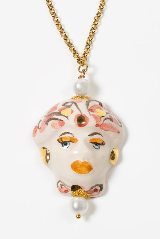 Collar largo de cadena dorada con perlas naturales y nudos de hilo blanco, con colgante de cerámica pintado a mano con rostro barroco.