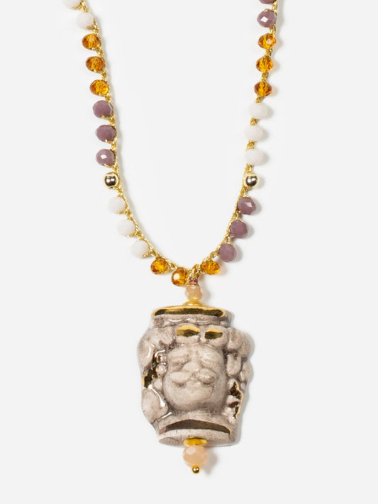 Collar largo con cuentas en tonos mostaza, lavanda y blanco, y colgante de busto masculino de cerámica pintado a mano. Cierre dorado con perla decorativa.