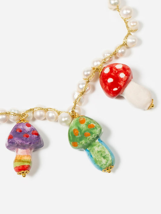 Collar corto de perlas naturales trenzadas con hilo dorado, con cinco colgantes de hongos multicolores esmaltados. Fondo blanco. Cashfana.