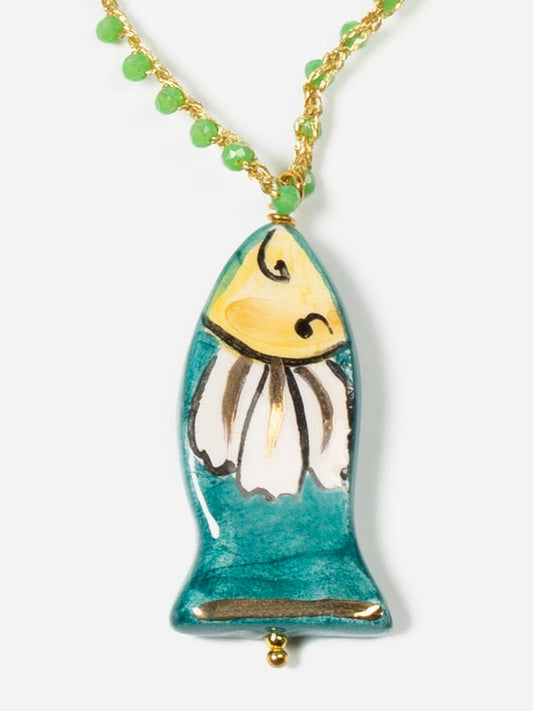 Detalle de collar mini pez verde con cordón en hilo dorado de crochet y cuentas verdes entrelazadas con pieza de cerámica con forma de pez sobre fondo blanco.