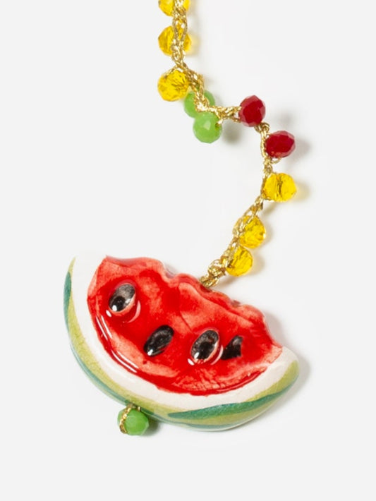 Collar largo con cuentas en colores rojo, verde y amarillo, con colgante de cerámica en forma de sandía, sobre fondo blanco. Cashfana.