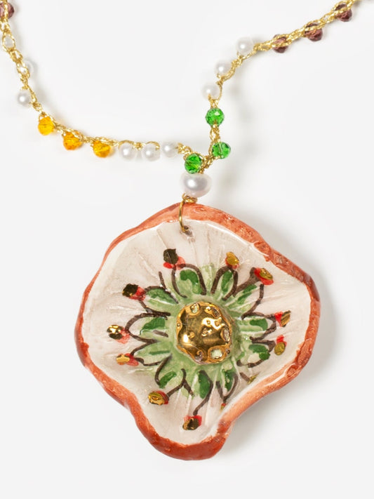 Collar Miranda largo con colgante esmaltado en forma de sol en tonos dorado, verde y terracota, cadena de cuentas en verde, lila, blanco y amarillo, sobre fondo blanco. Cashfana.