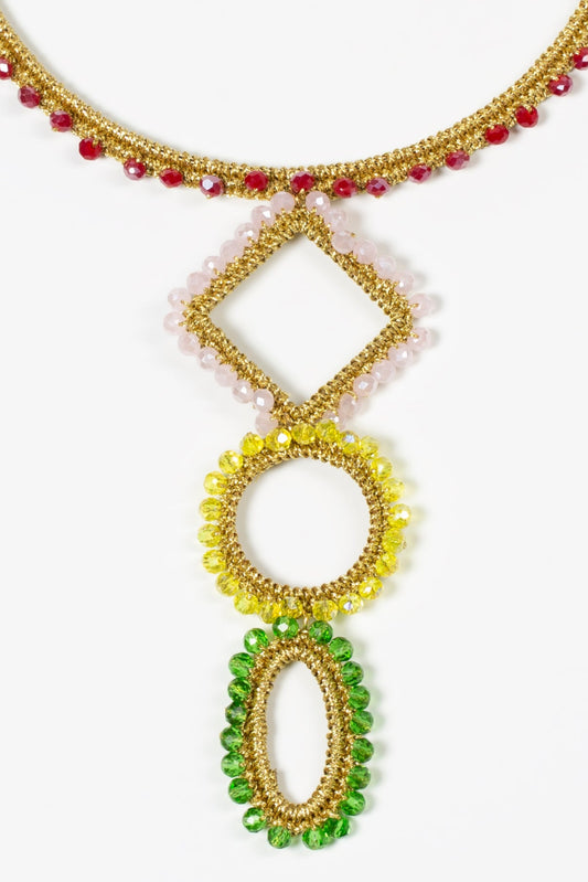 Detalle de tres formas geométricas: rombo con cuentas rosas, círculo con cuentas amarillas y óvalo con cuentas verdes. Todos adornados con hilo dorado.