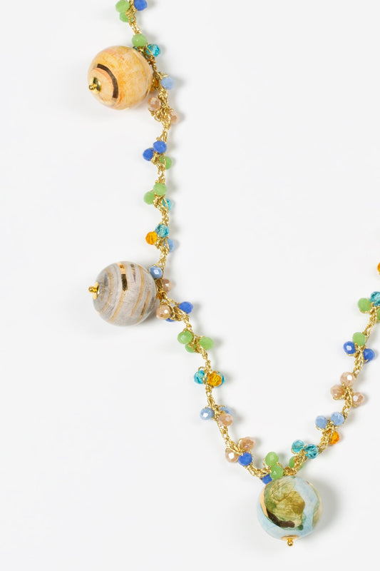 Tres esferas amarilla beige y verde y azul de cerámica pintadas a mano que simulan planetas, sobre fondo blanco. Cashfana.