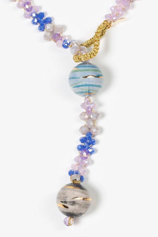 Dos esferas de cerámica tipo planetas en azul y gris con cierre dorado y hilo trenzado con cuentas lilas y azules. Cashfana.