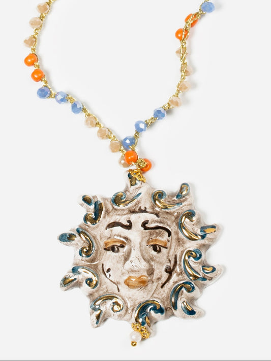 Colgante de cerámica esmaltada en forma de sol con rostro humano, en tonos tierra, crema y metálicos. Cashfana.