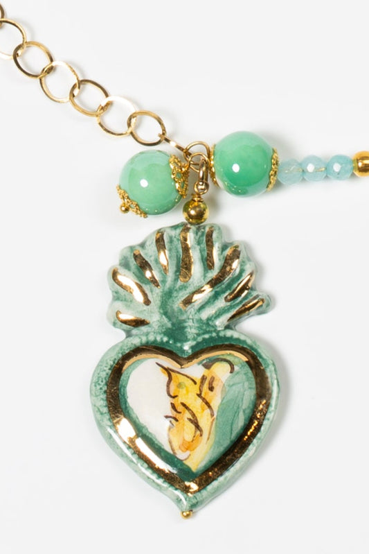 Colgante de cerámica en forma de corazón verde con flama superior e interior dorado, sobre fondo blanco.
Cashfana.