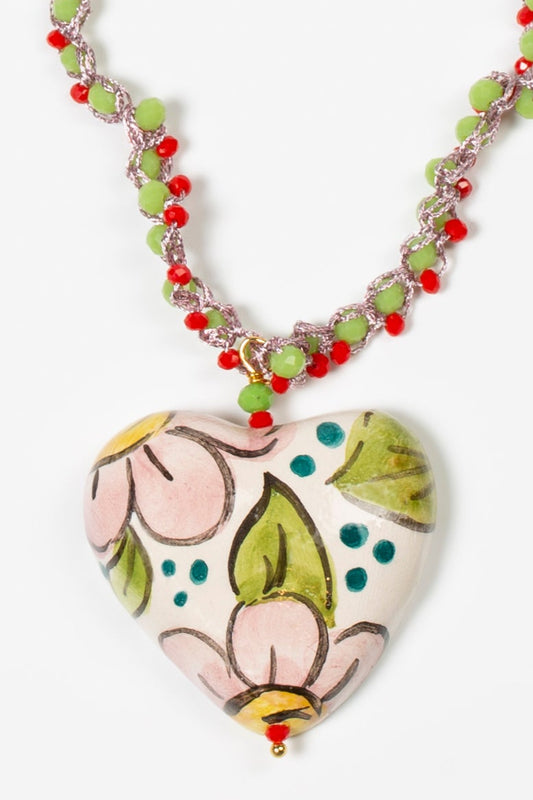 Detalle del colgante de cerámica en forma de corazón pintado a mano con flores, montado en collar de cuentas rojas y verdes Cashfana.