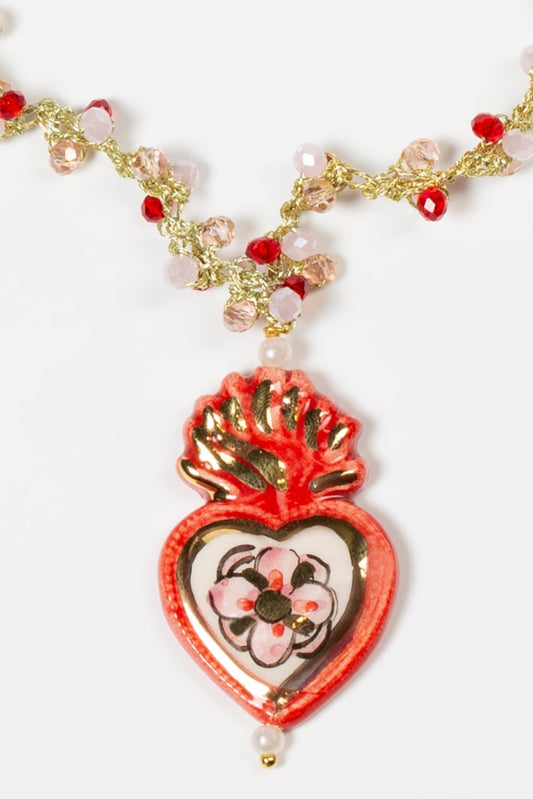 Colgante de cerámica en forma de corazón rojo decorado con flores y corona de fuego, sobre fondo blanco. Cashfana.