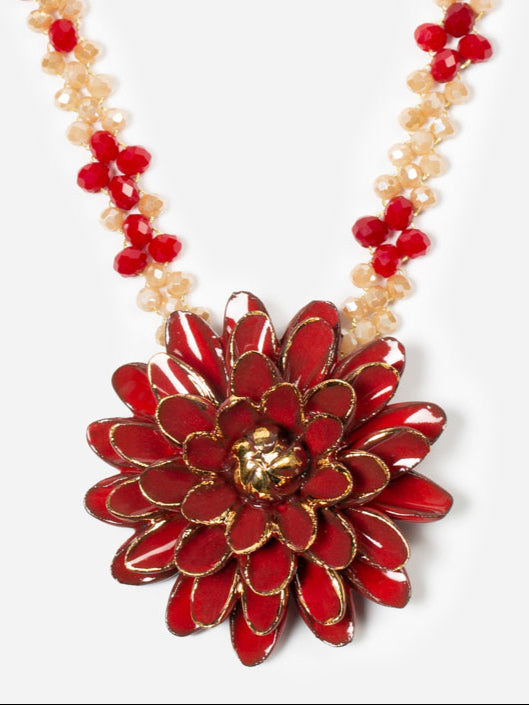Collar Isabella con con colgante de flor esmaltada en rojo intenso y detalles dorados, sobre fondo blanco. Cashfana.