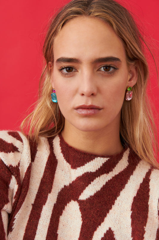 Pendientes con cristales rectangulares en azul claro y rosa pastel, con piezas superiores en verde esmeralda y rosa fucsia. Diseño llamativo y elegante.
Con modelo combinado con jersey en tonos granate y blanco.