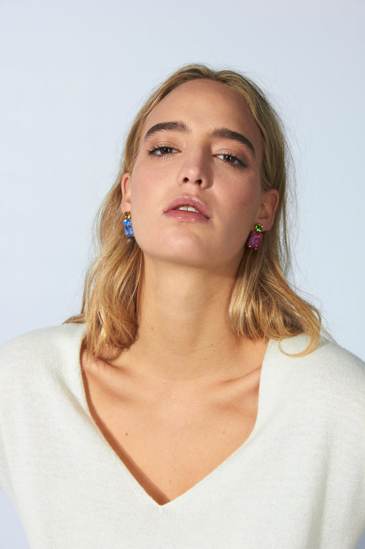 Pendientes colgantes con cristales rectangulares en rosa y azul, combinados con piedras redondas en verde y ámbar. Con modelo y jersey blanco.