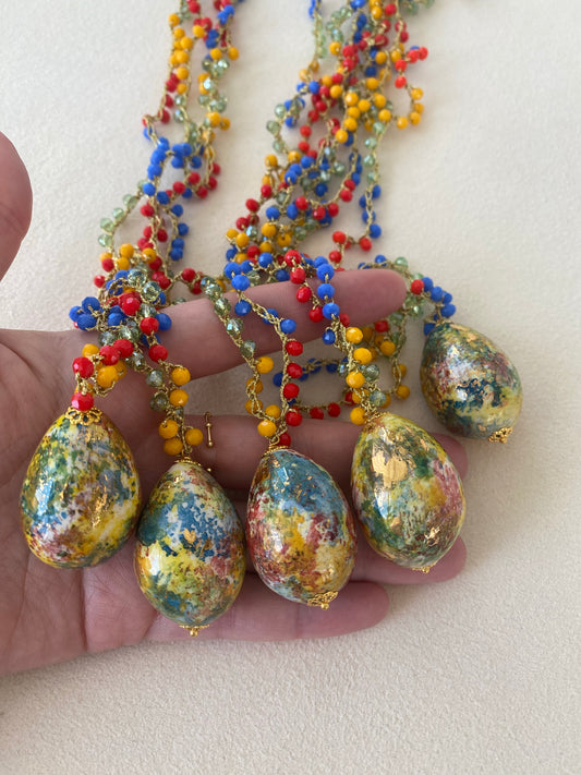 Collar con cuentas de colores vivos y colgante en forma de huevo pintado a mano. Cinco de ellos para que se pueda apreciar su autenticidad. Diseño artesanal y único de Cashfana.