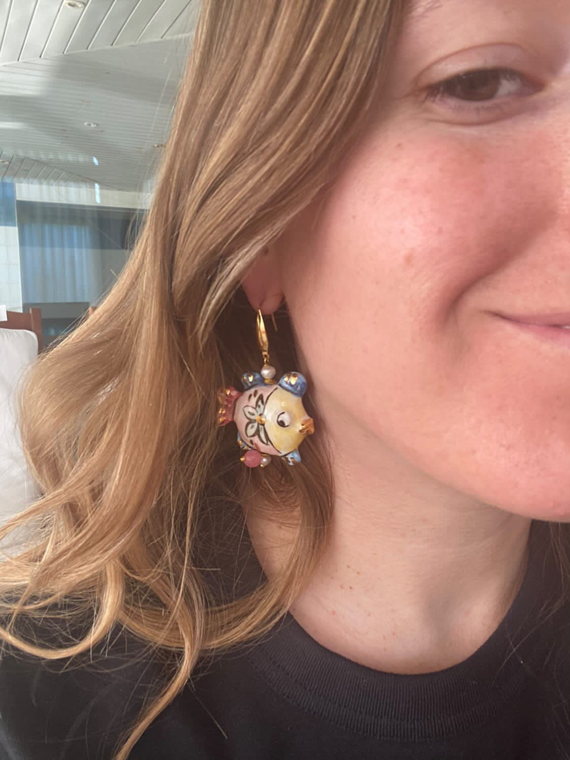 Pendientes artesanales en forma de pez, esmaltados a mano en tonos rosa, amarillo y azul con detalles florales.