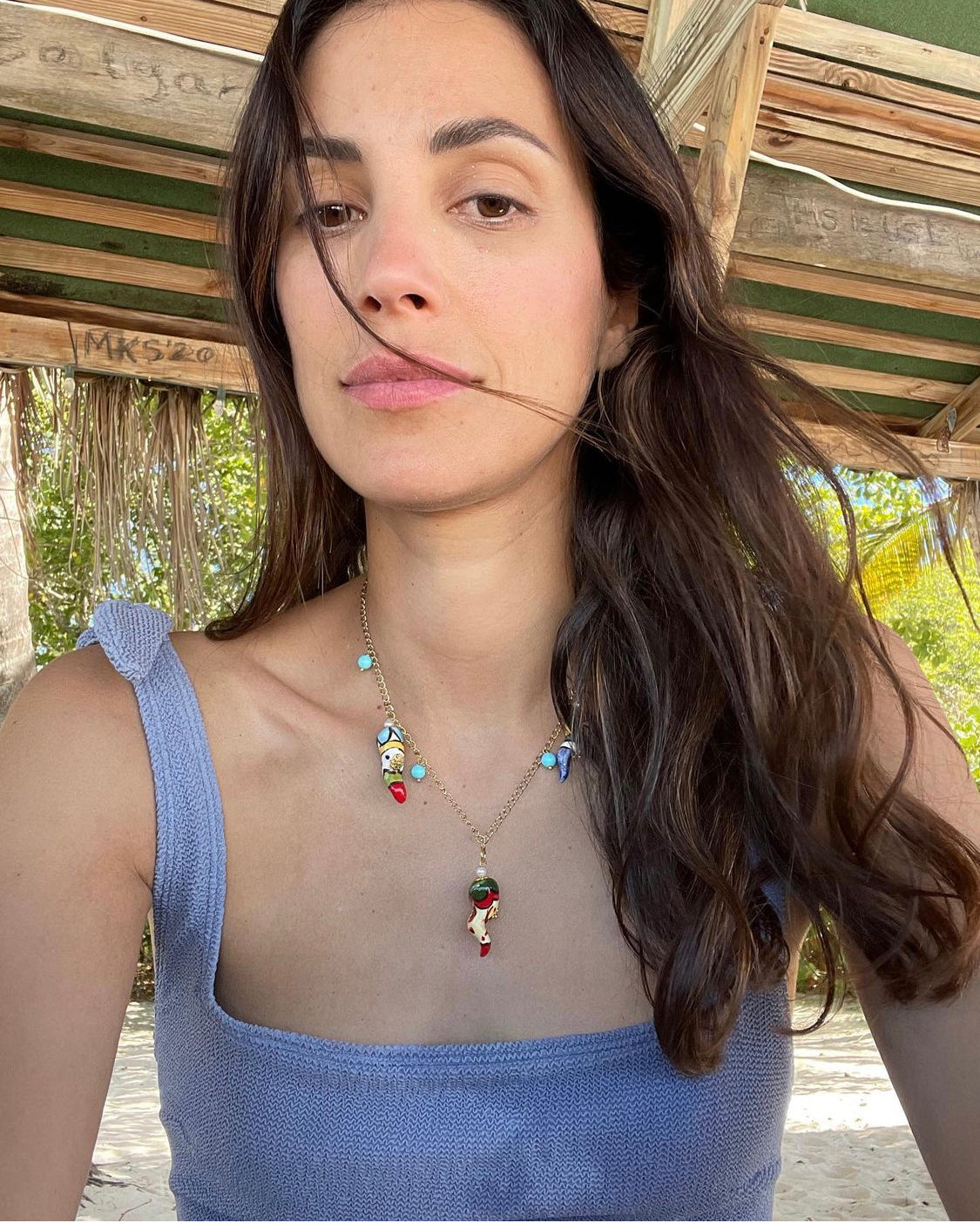 Collar corto de cadena dorada con cuentas turquesa y colgantes de pimientos esmaltados en distintos colores.
Con top azul. Cashfana.