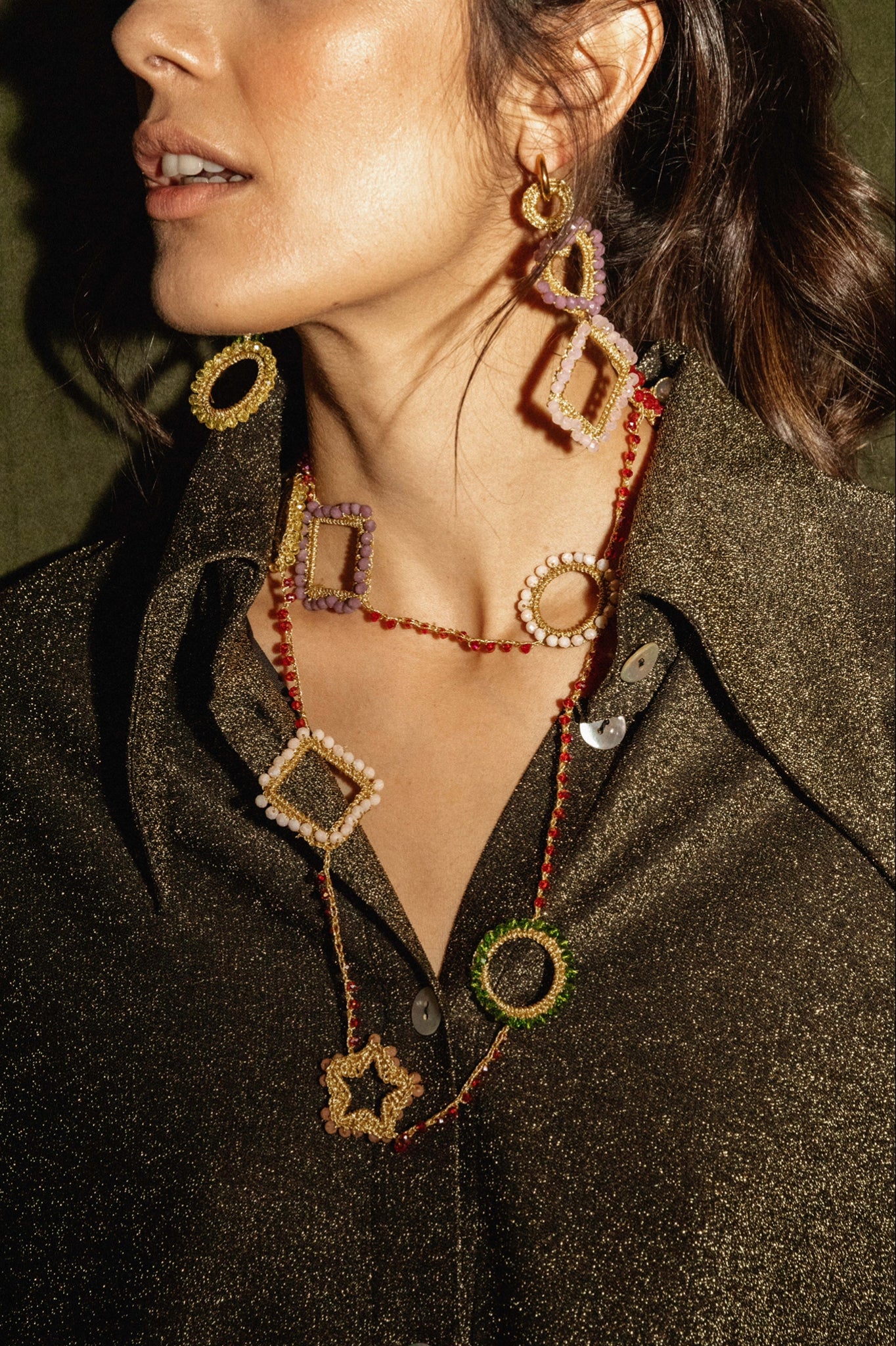 Pendientes geométricos asimétricos con cuentas de colores en forma de corazón, rombo, óvalo y círculo. Combinados con el collar geométrico y un jersey de purpurina negro.