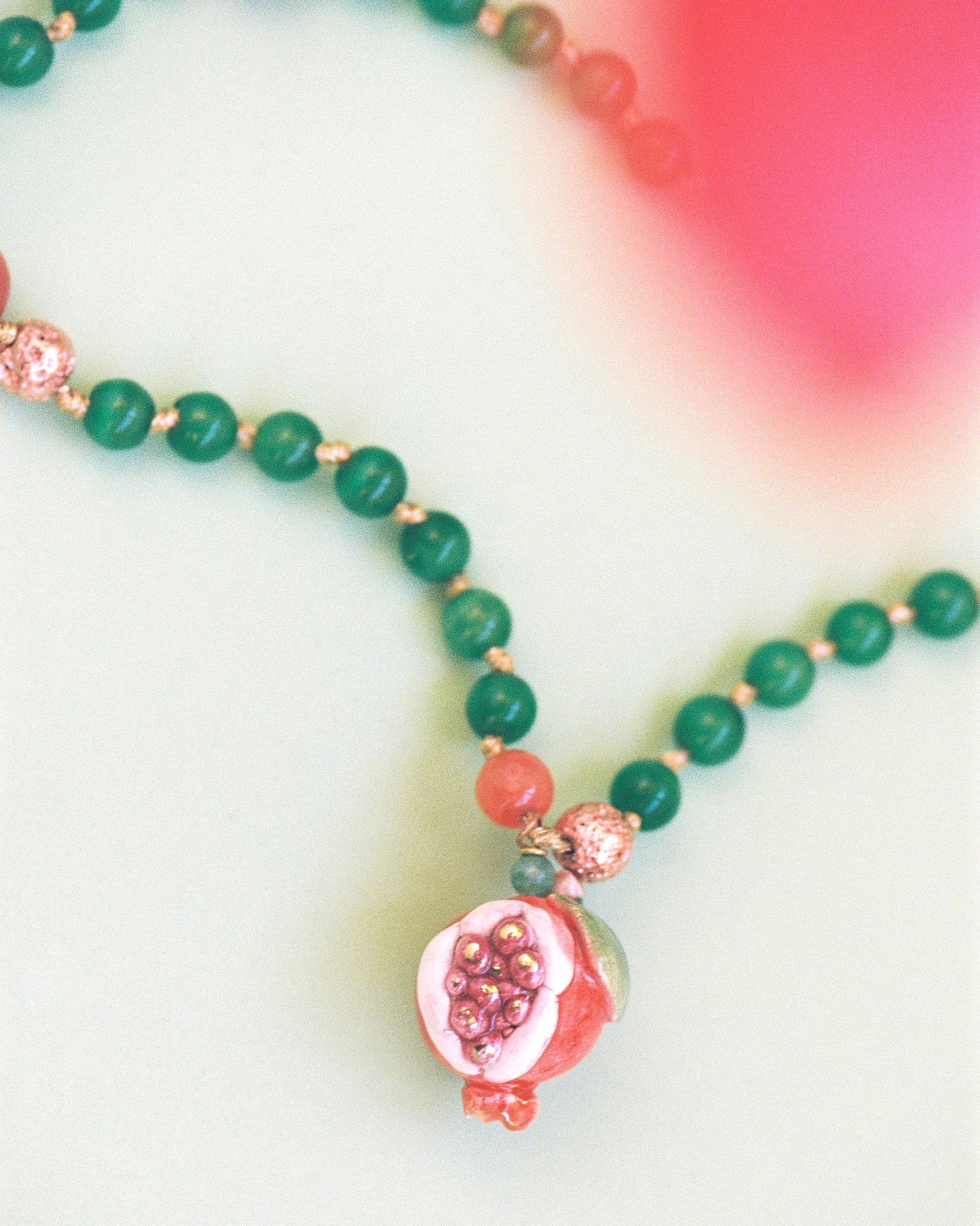 OPEN POMEGRANATE, LONG GREEN AND RED BEAD NECKLACE WITH PIECE OF CERAMIC IN THE SHAPE OF A POMEGRANATE