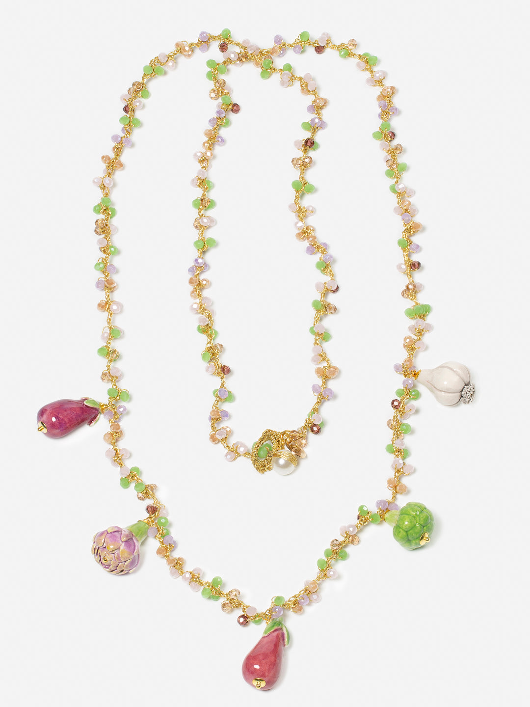 Collar largo de cuentas en tonos ámbar, verde y lila, con cuatro charms colgantes de cerámica: berenjena morada, alcachofa verde, pimiento rojo y cebolla blanca y brócoli sobre fondo blanco. Cashfana.

